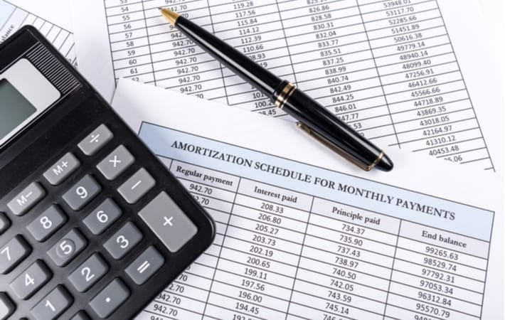 Amortization schedule documents with a calculator and a pen laying on top