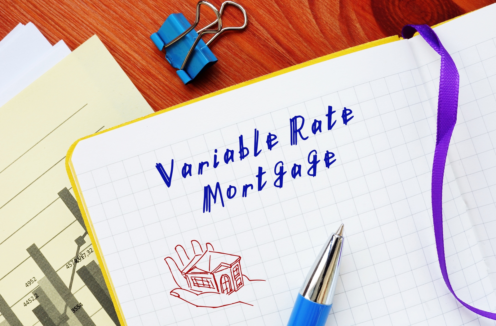 A notepad with the words "variable rate mortgage" written on the page beside a drawing of a hand holding a small house