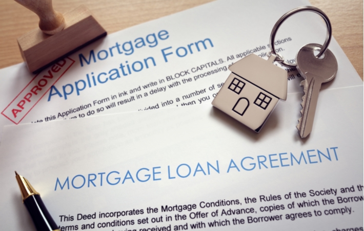 A mortgage loan agreement on top of a mortgage application form that has been stamped approved