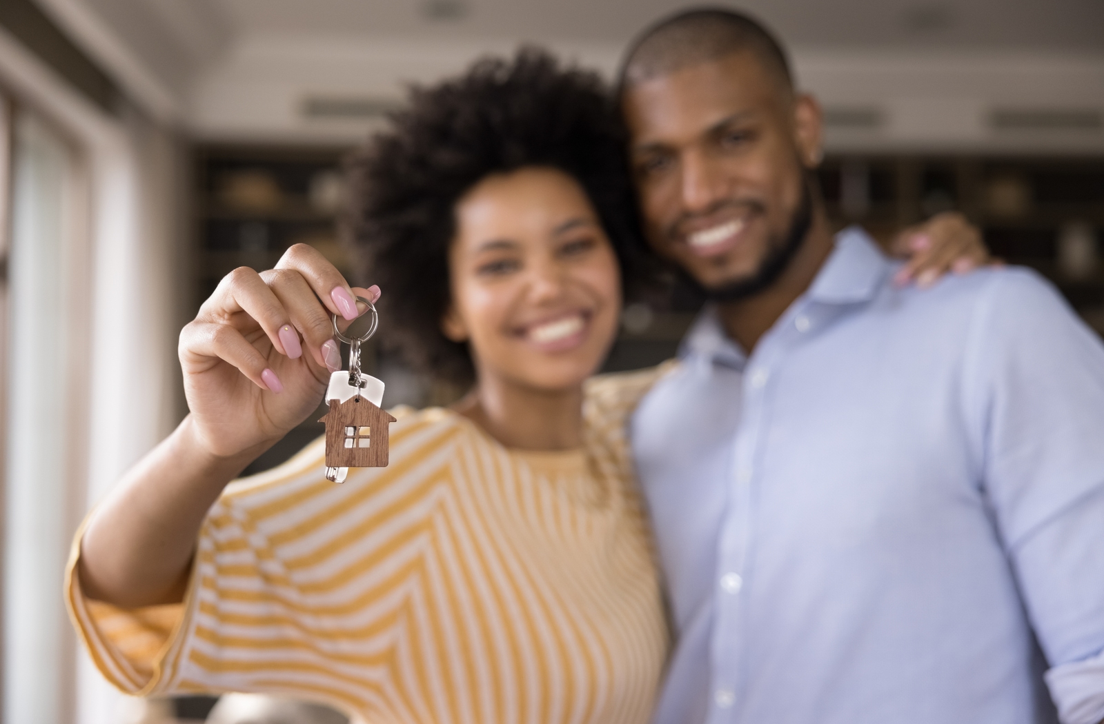 A young couple smiling while they hold the keys to their new house