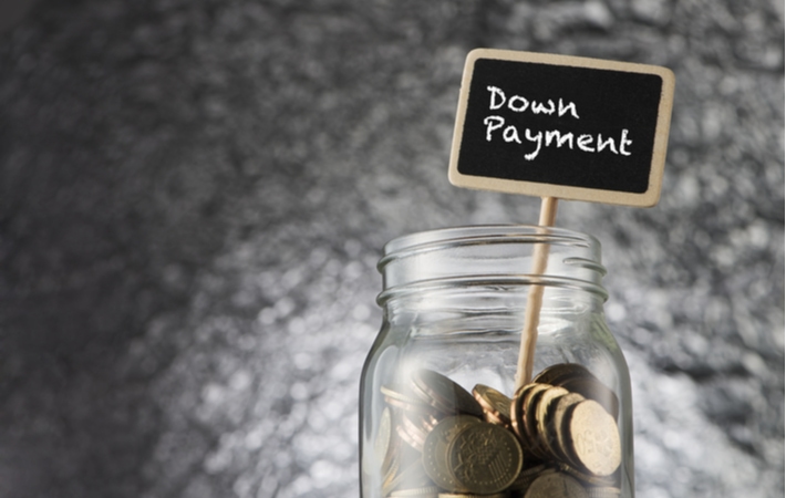 A jar of coins with a small sign sticking out of the jar reading "down payment"