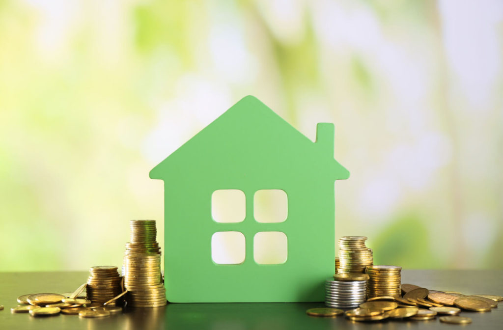 Image of green, tiny wooden home facade with pennies on the side to show that porting a mortgage can save you money