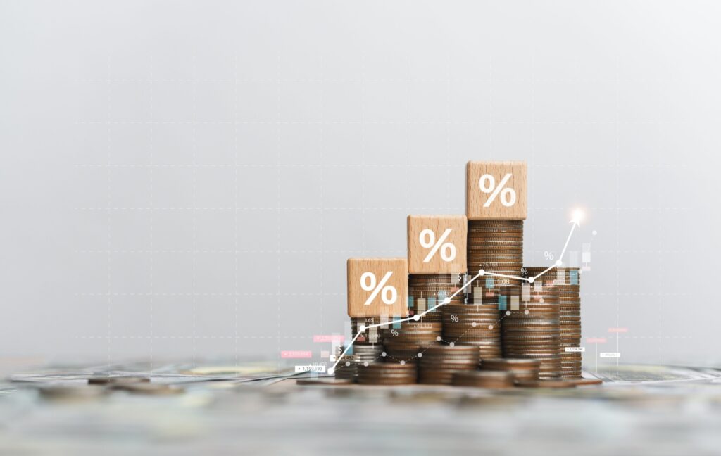 A few piles of coins sit on a table. A graph set over the coins shows an upward trend and financial improvement.