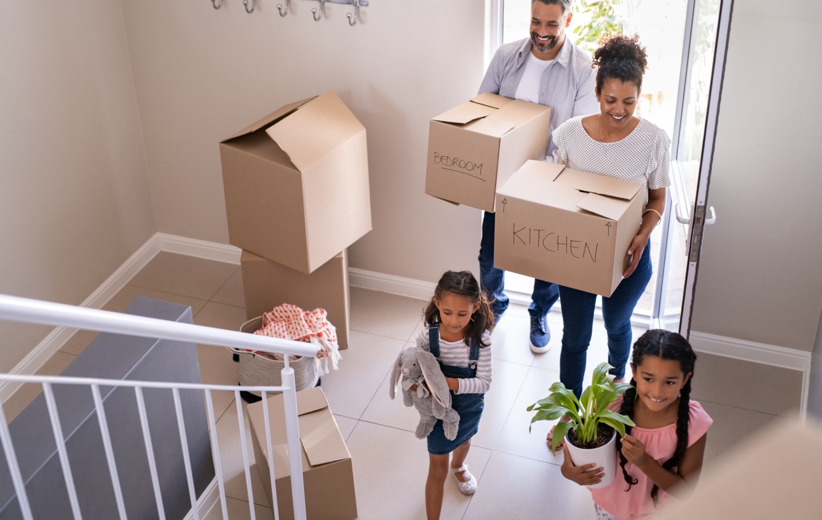 A couple and their two young children move cardboard boxes into the entry way of their new home in Canada.