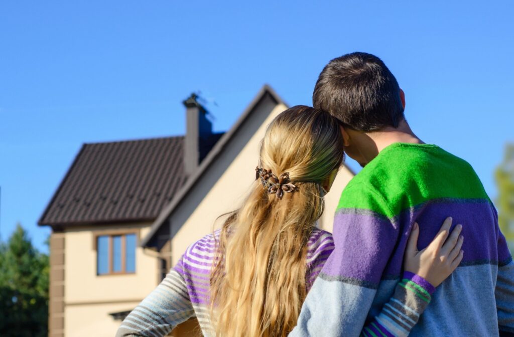 A young couple of first-time home buyers look at their new home together.