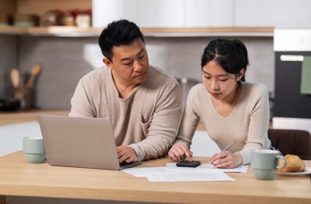 Couple reviewing finances at home with laptop, calculator, and mortgage documents