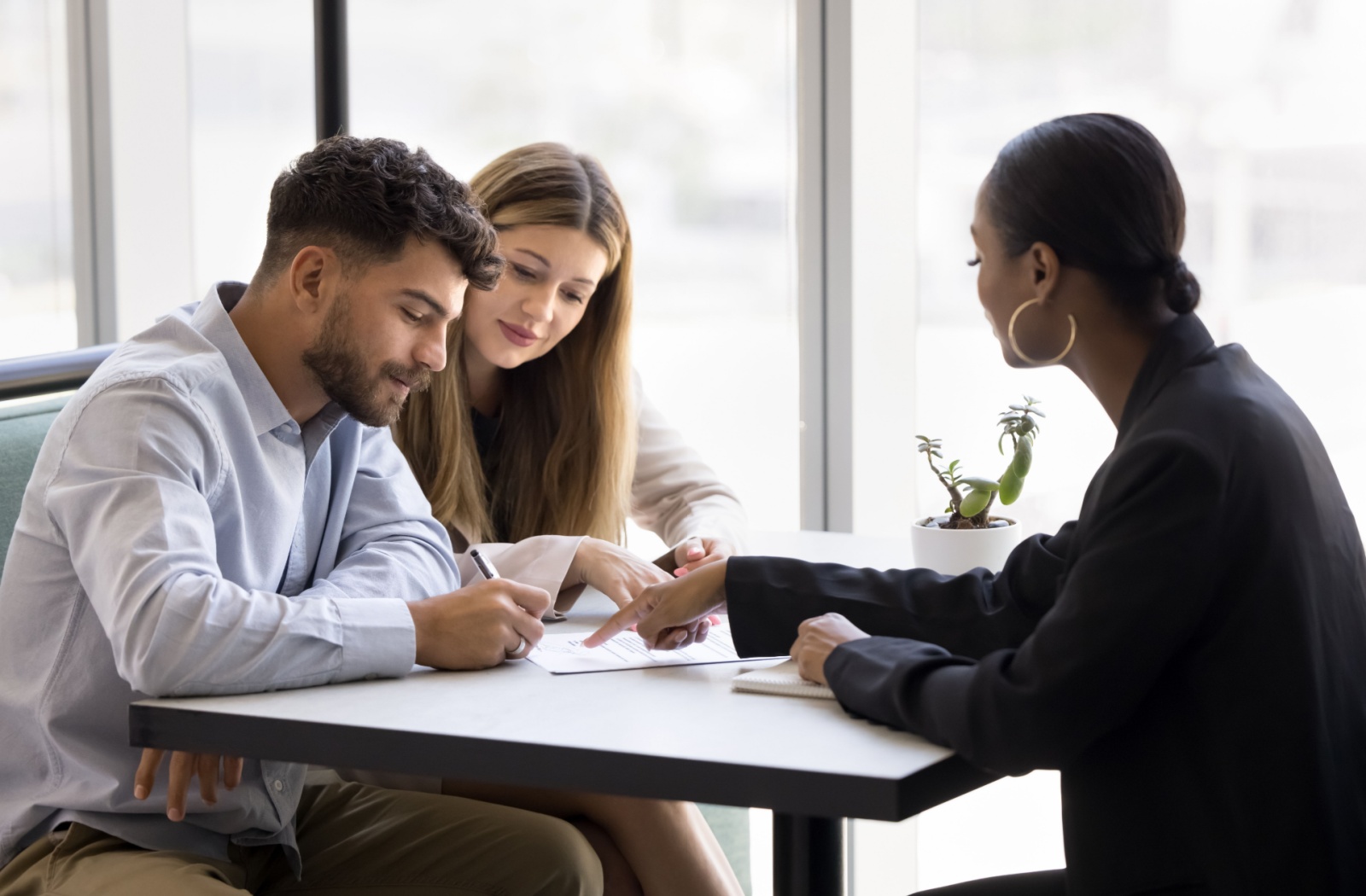 Two people sitting with a mortgage broker discussing their TDS ratio and mortgage options.