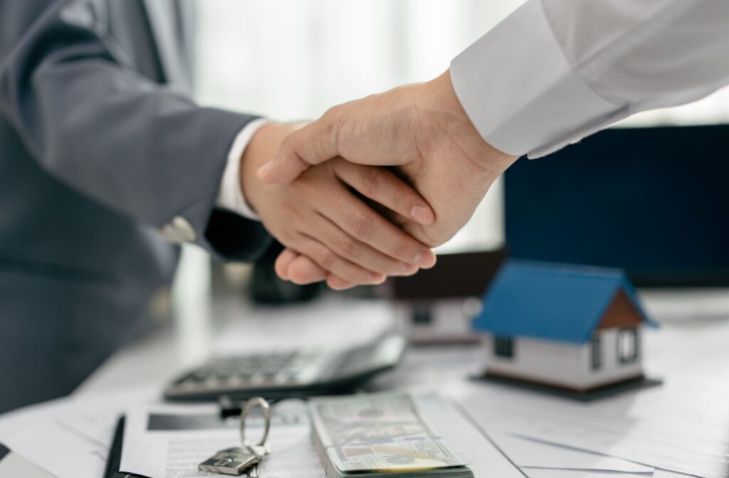 A mortgage broker shaking hands with a client over a mortgage renewal.