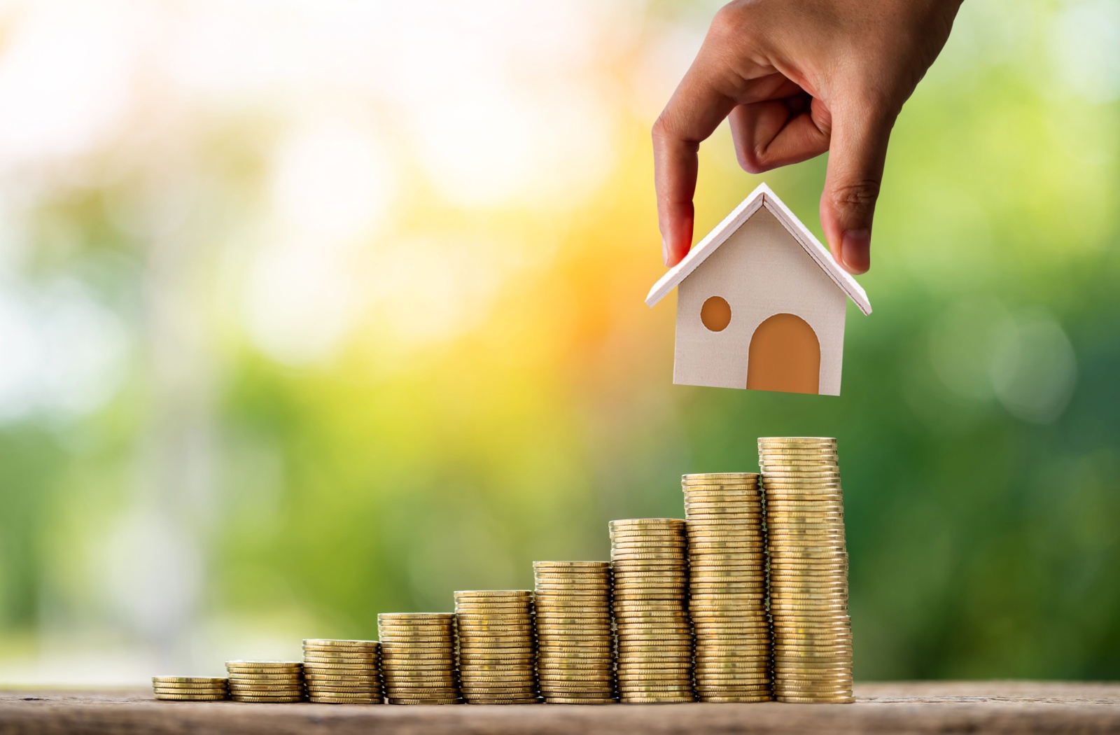 A model home being set on a stack of coins, showing the benefits of property investment.