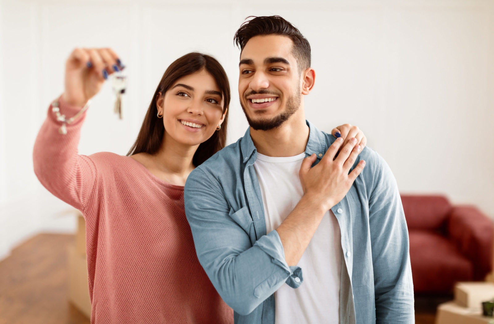 A couple holding up keys to the new home they purchased.
