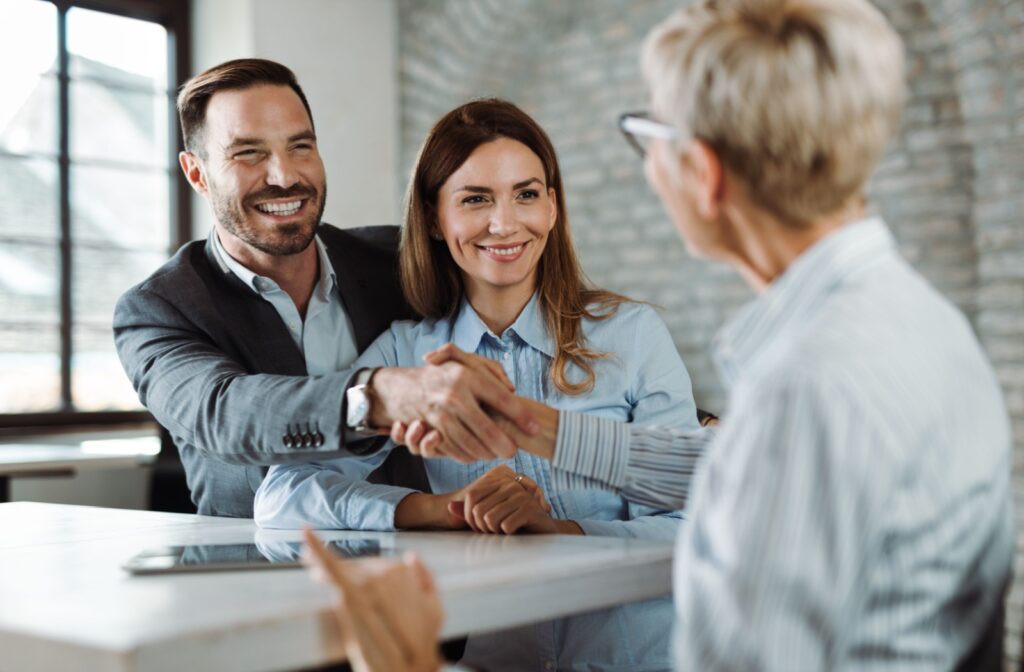 A mortgage broker shaking hands with a client after helping them with their mortgage.