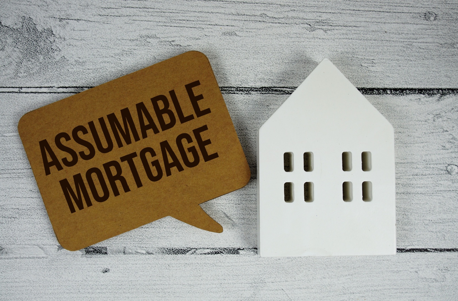 A sign that says assumable mortgages beside a model of a house